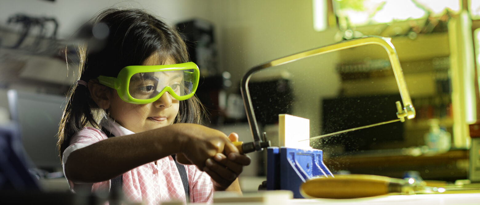 child sawing up a piece of wood