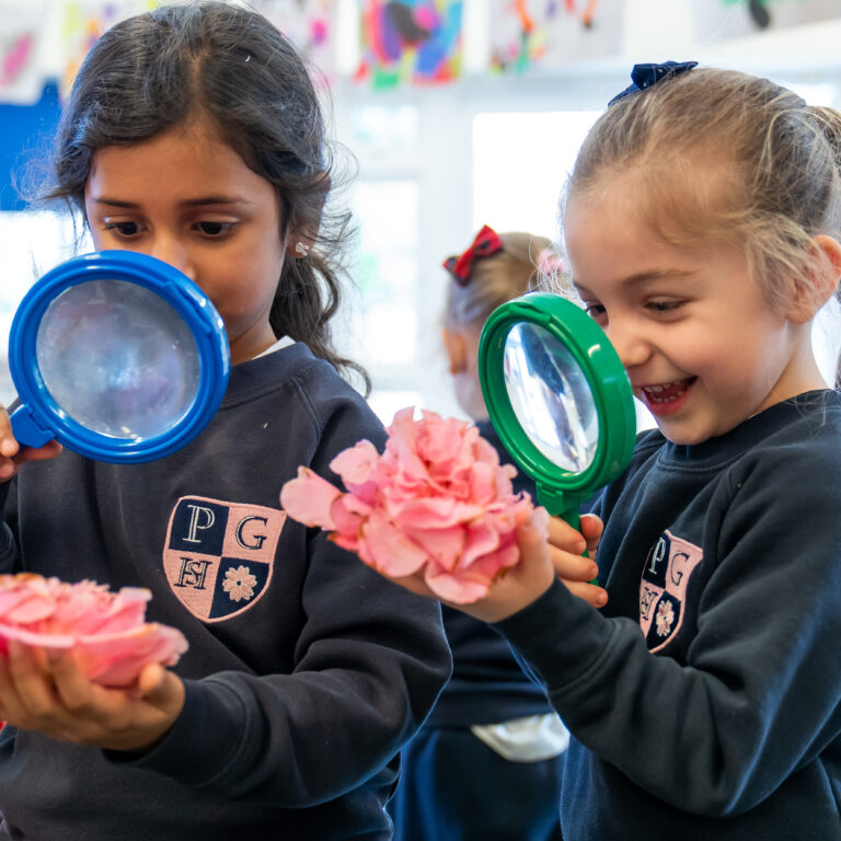 nursery students looking at a flower using a magnifying glass